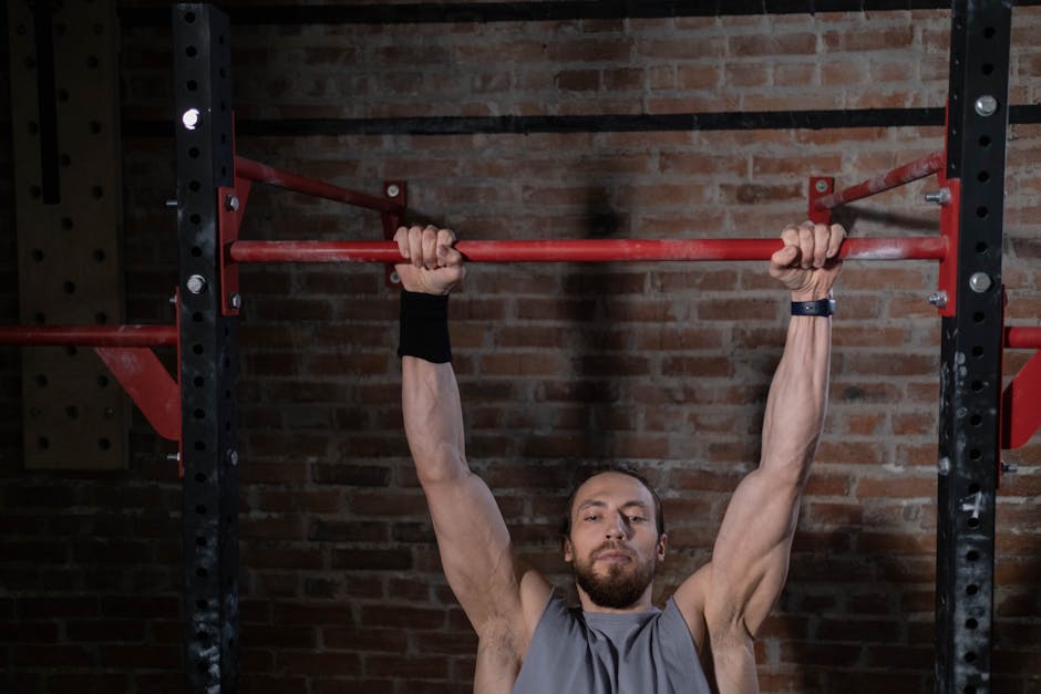 Man exercising on pull-up bar in gym, showcasing strength and fitness.
