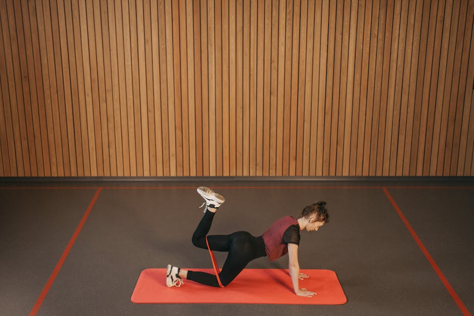 Woman performing a resistance band workout on a mat indoors, focusing on fitness and strength